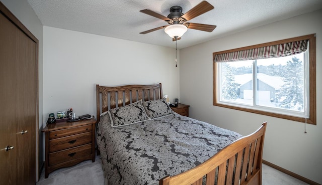 carpeted bedroom featuring ceiling fan, a textured ceiling, and a closet