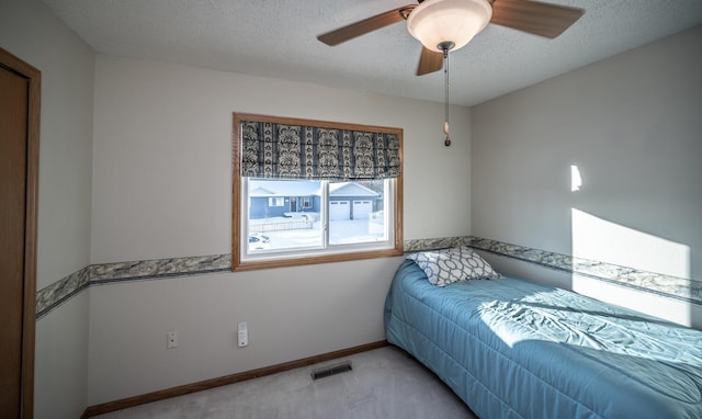 bedroom featuring light carpet, a textured ceiling, and ceiling fan