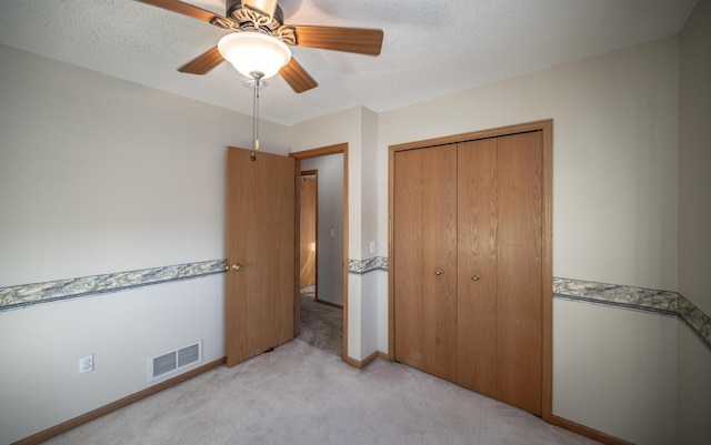 carpeted bedroom with a textured ceiling, a closet, and ceiling fan