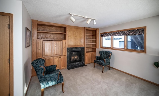 sitting room with a high end fireplace, light colored carpet, a textured ceiling, and rail lighting