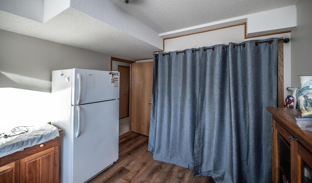 kitchen featuring a textured ceiling, white fridge, and dark wood-type flooring