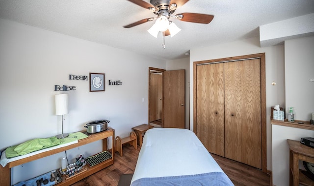 bedroom featuring ceiling fan, a closet, dark wood-type flooring, and a textured ceiling