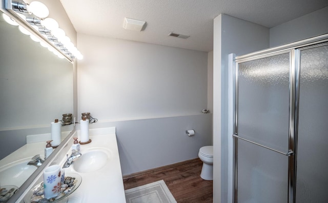 bathroom with vanity, hardwood / wood-style flooring, toilet, a textured ceiling, and a shower with shower door