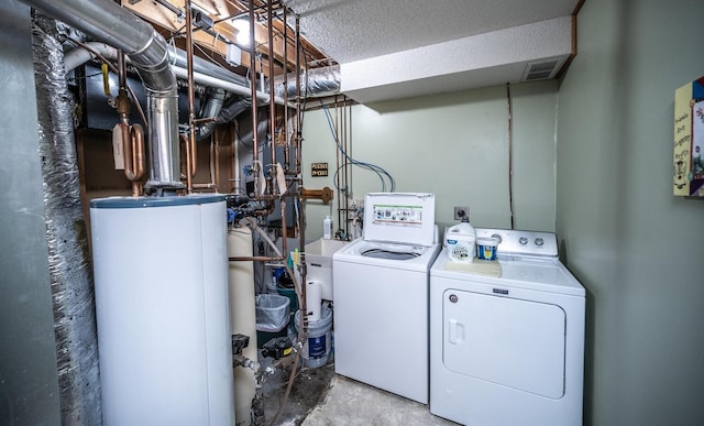 laundry room featuring separate washer and dryer, water heater, and a textured ceiling