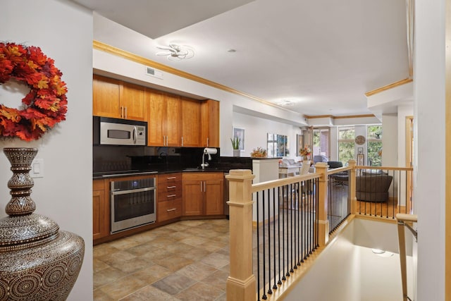 kitchen with stainless steel appliances, sink, kitchen peninsula, ornamental molding, and tasteful backsplash