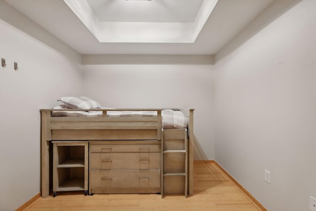 bedroom with a tray ceiling and hardwood / wood-style flooring