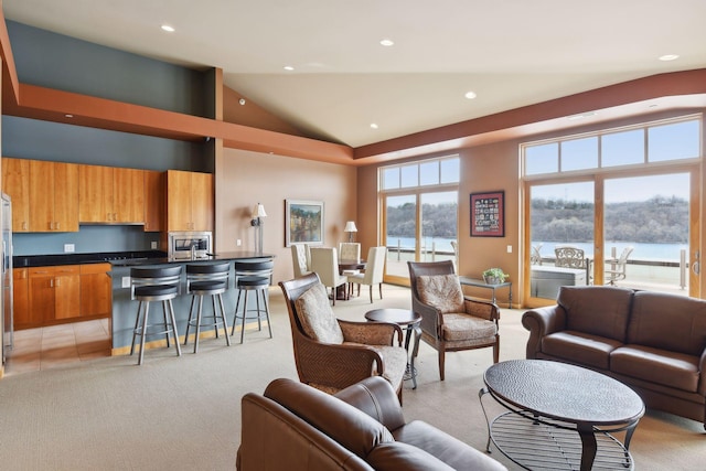 living room featuring light colored carpet, a water view, and high vaulted ceiling