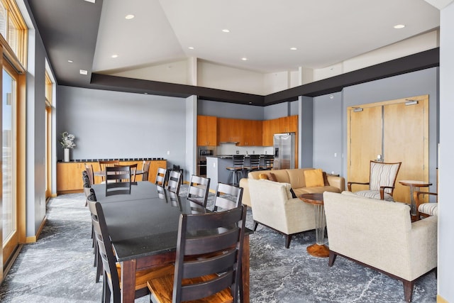 carpeted dining area with high vaulted ceiling