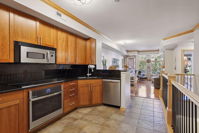 kitchen with a sink, ornamental molding, brown cabinetry, and stainless steel appliances