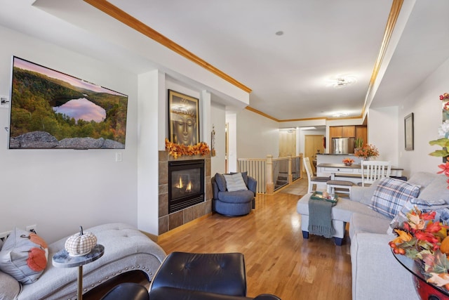 living area with crown molding, a fireplace, and light wood finished floors