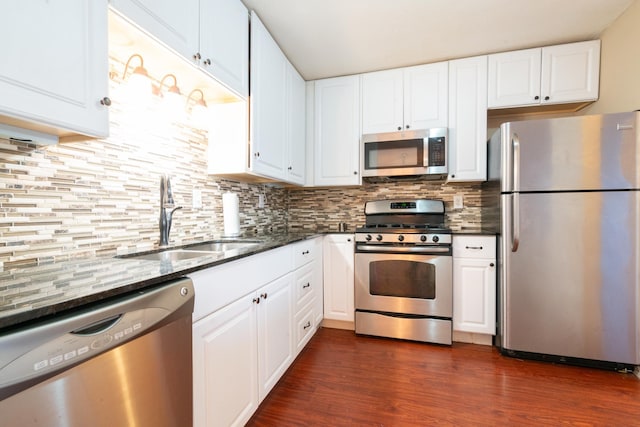 kitchen with white cabinets, appliances with stainless steel finishes, dark hardwood / wood-style floors, and sink