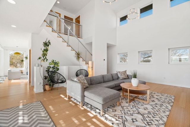 living area with recessed lighting, stairway, a towering ceiling, wood finished floors, and baseboards