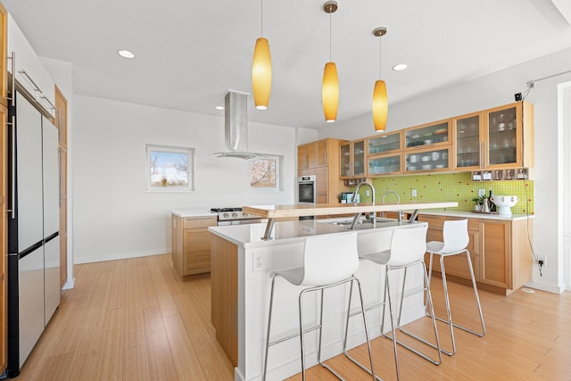 kitchen featuring light wood-style floors, a center island with sink, island range hood, and decorative backsplash