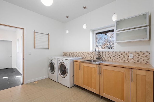 clothes washing area featuring cabinet space, baseboards, a sink, and washing machine and clothes dryer