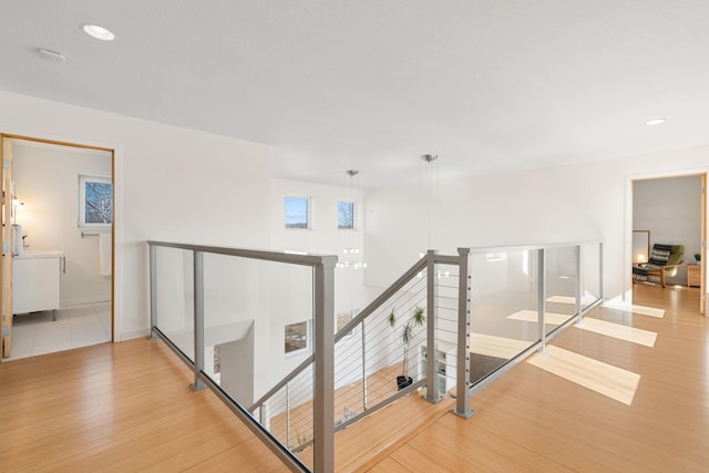 corridor with baseboards, wood finished floors, an upstairs landing, and recessed lighting