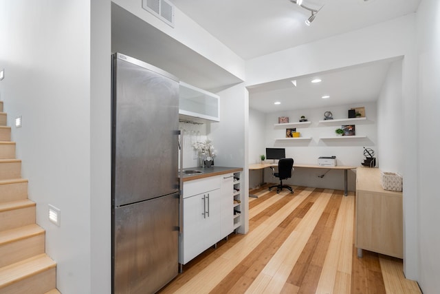 office space featuring light wood-type flooring, built in study area, visible vents, and recessed lighting