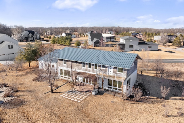 rear view of property featuring metal roof, a standing seam roof, and a balcony