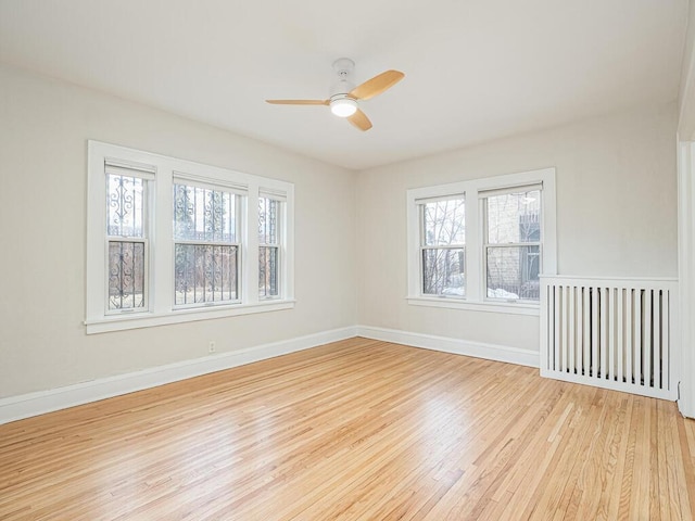 spare room featuring light wood-type flooring, ceiling fan, and a wealth of natural light