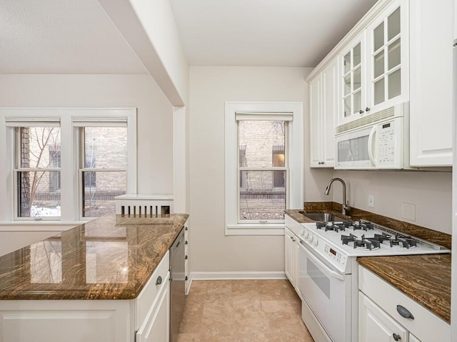 kitchen with white appliances, sink, dark stone countertops, and white cabinetry