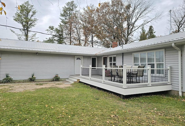 rear view of property with a wooden deck and a lawn