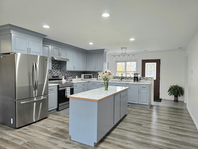 kitchen featuring gray cabinets, a center island, light hardwood / wood-style flooring, and stainless steel appliances