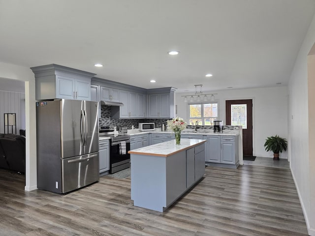 kitchen with gray cabinets, a center island, stainless steel appliances, and light wood-type flooring