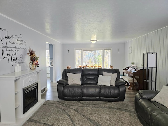 living room featuring ornamental molding, a textured ceiling, hardwood / wood-style flooring, and wooden walls