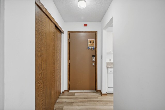 doorway to outside with light hardwood / wood-style floors and a textured ceiling