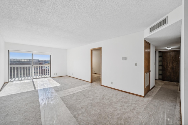 spare room featuring light carpet and a textured ceiling