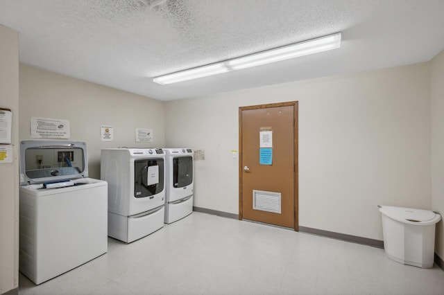 laundry room featuring a textured ceiling and separate washer and dryer