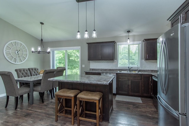 kitchen with appliances with stainless steel finishes, dark hardwood / wood-style flooring, a healthy amount of sunlight, and a kitchen island