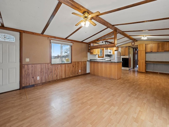 unfurnished living room with vaulted ceiling with beams, wood walls, ceiling fan, and light hardwood / wood-style floors