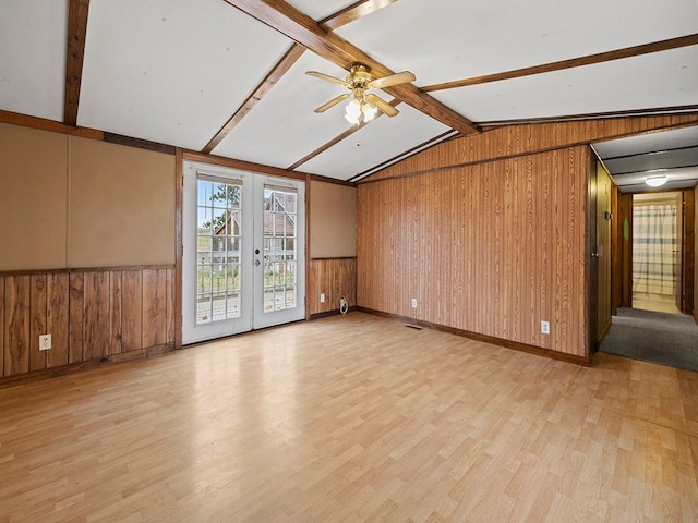 spare room with french doors, lofted ceiling with beams, light hardwood / wood-style flooring, and wood walls