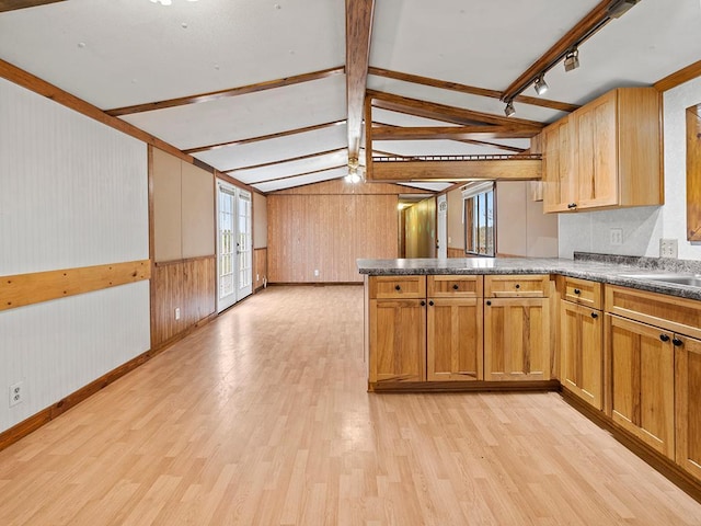 kitchen with french doors, lofted ceiling with beams, kitchen peninsula, light hardwood / wood-style floors, and wooden walls