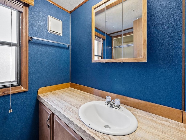 bathroom with vanity, a textured ceiling, and a healthy amount of sunlight