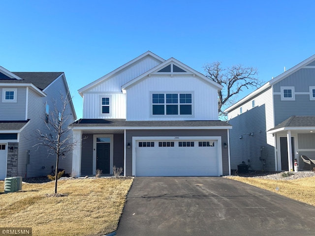 view of front of house featuring a garage, cooling unit, and a front yard