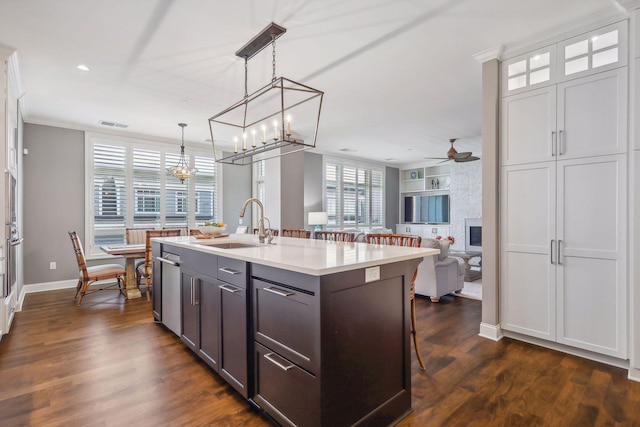 kitchen with dark hardwood / wood-style floors, a breakfast bar, decorative light fixtures, an island with sink, and white cabinets