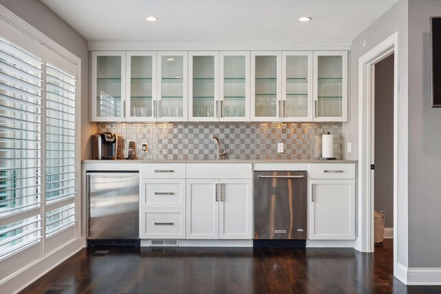 bar featuring backsplash, stainless steel fridge, sink, and white cabinets