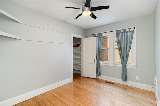 unfurnished bedroom with ceiling fan, multiple windows, a closet, and light wood-type flooring