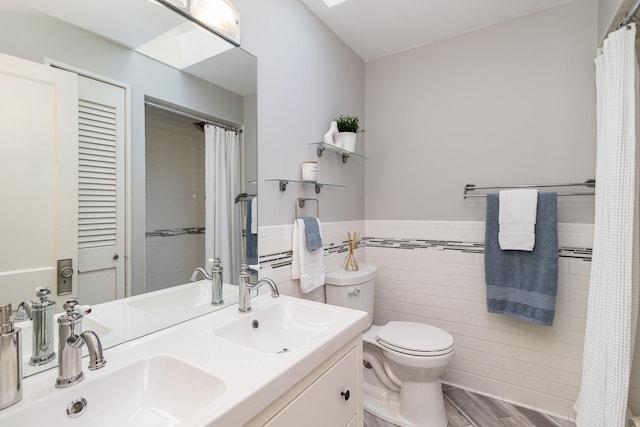 bathroom with toilet, vanity, and tile walls