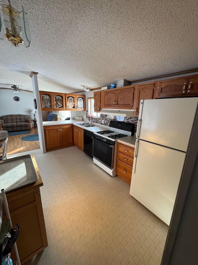 kitchen with a textured ceiling, dishwasher, range with gas stovetop, white fridge, and sink