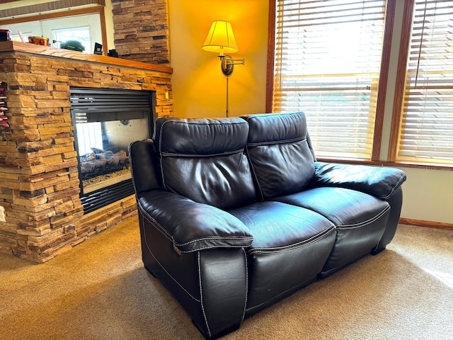 sitting room featuring a stone fireplace and carpet