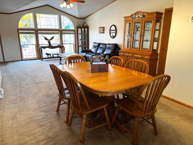 carpeted dining space with ceiling fan, ornamental molding, and vaulted ceiling