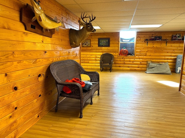 living area with a paneled ceiling, log walls, and light wood-type flooring