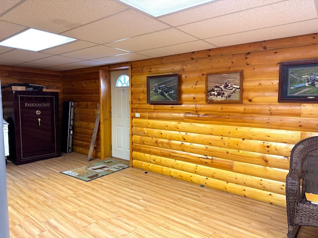 interior space featuring a paneled ceiling, light wood-type flooring, and log walls