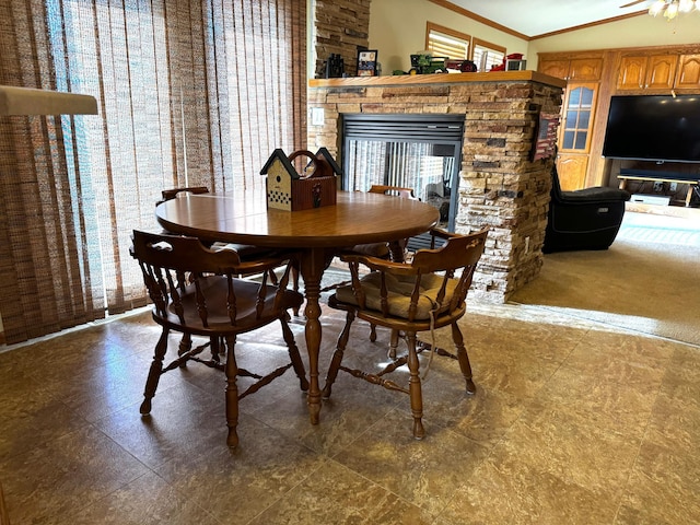 dining room featuring a stone fireplace, ornamental molding, and lofted ceiling