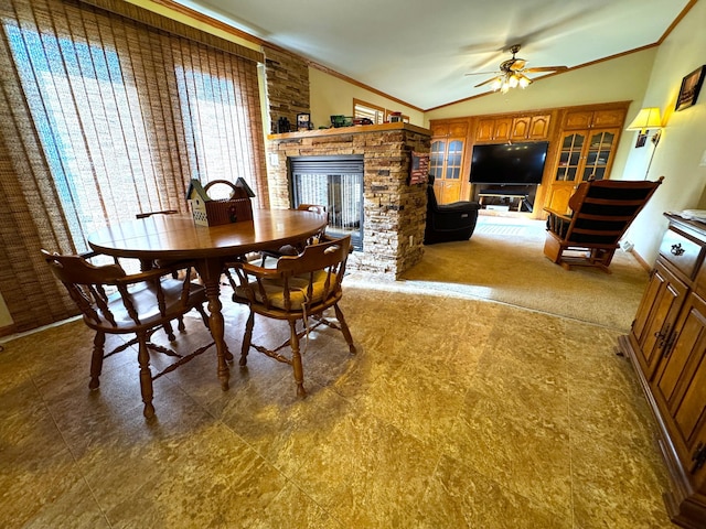 dining room with a stone fireplace, a wealth of natural light, ornamental molding, vaulted ceiling, and ceiling fan