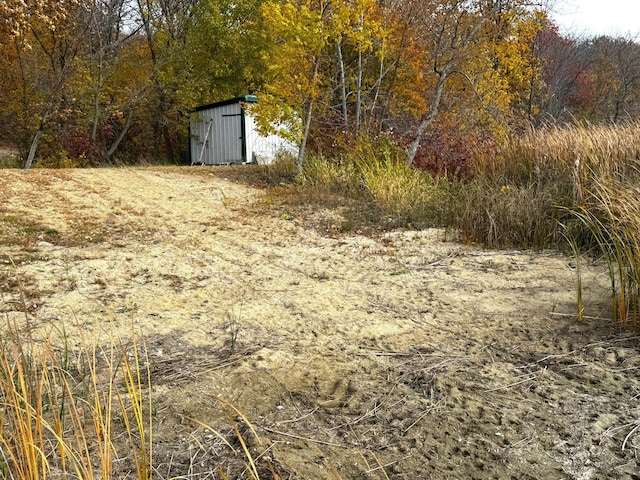 view of yard featuring an outbuilding, a wooded view, and a storage unit