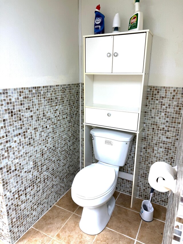 bathroom featuring tile patterned floors, toilet, tile walls, and wainscoting