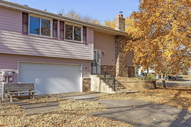 view of front of home with brick siding, a chimney, and an attached garage